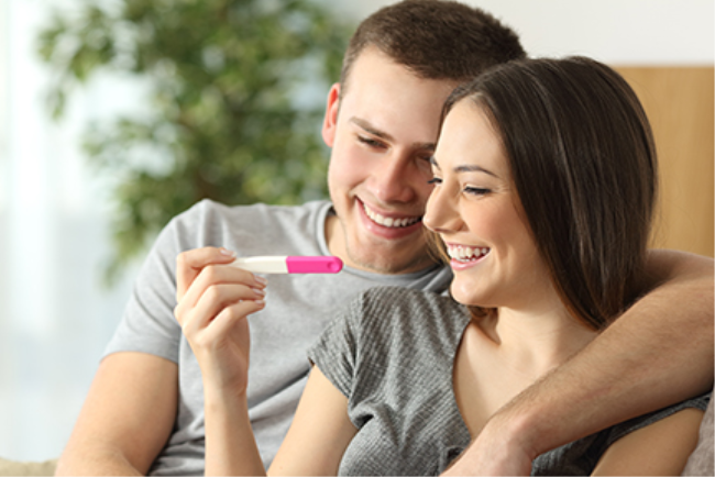 זוג מביט על בדיקת הריון חיובית ושמח לקראת ההריון העתידי